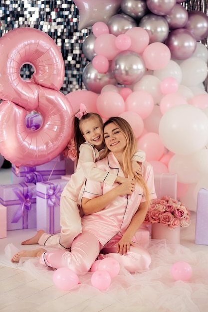 Familia feliz madre e hija en pijama con globos celebran el cumpleaños de los niños