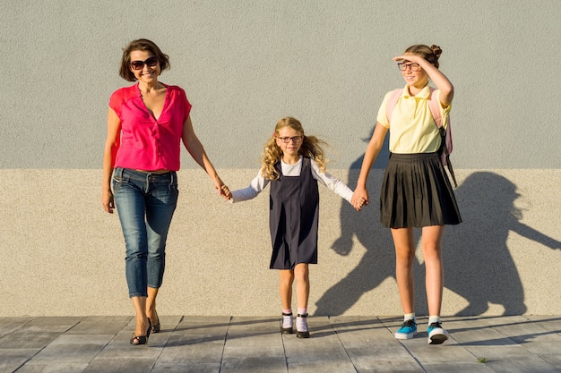 Familia feliz madre e hijas van a la escuela, comienzan a estudiar