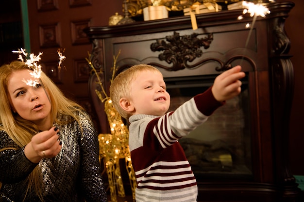 Familia feliz madre e hijo con bengala cerca de un árbol de Navidad