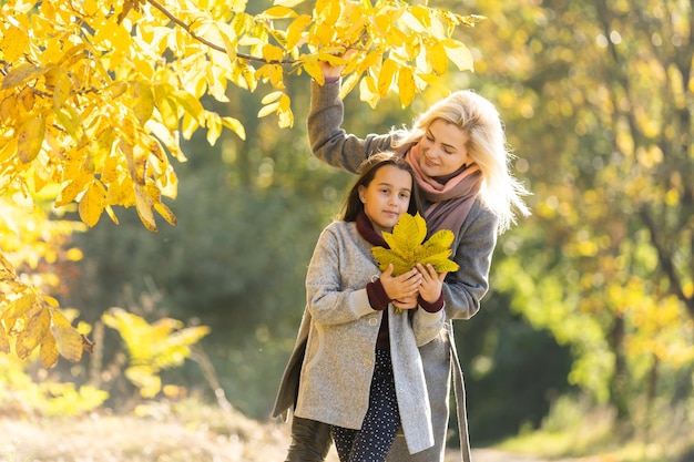 familia feliz: madre e hijo pequeña hija juegan en el paseo de otoño en la naturaleza al aire libre.