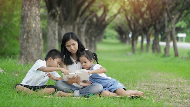 Familia feliz, madre hija e hijo unen actividades por libro leído en el jardín