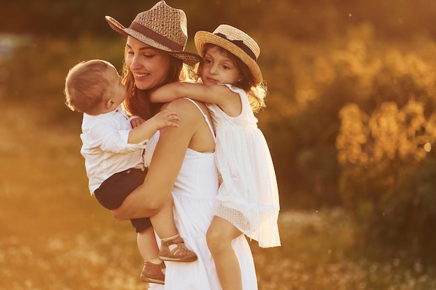 Familia feliz de madre hijo pequeño e hija que pasan tiempo libre en el campo en el día soleado del verano