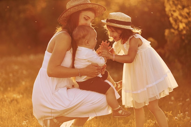 Familia feliz de madre hijo pequeño e hija que pasan tiempo libre en el campo en el día soleado del verano