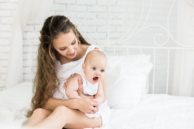 Familia feliz. Madre jugando con su bebé en el dormitorio.