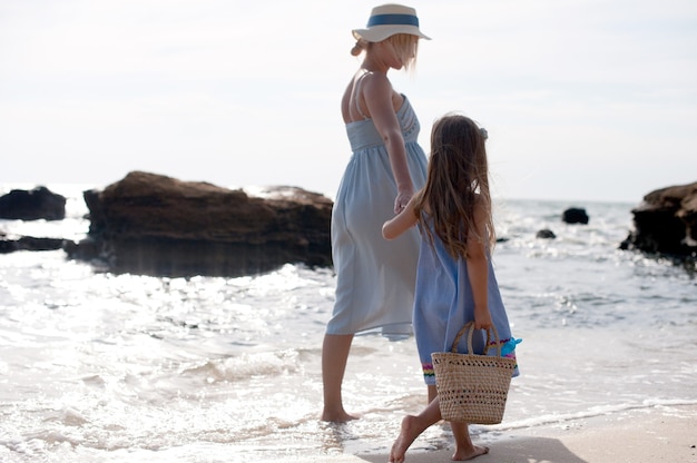 Familia feliz - madre y niña caminando cerca del mar