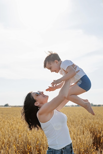 Familia feliz de madre y niño pequeño caminando en el campo de trigo