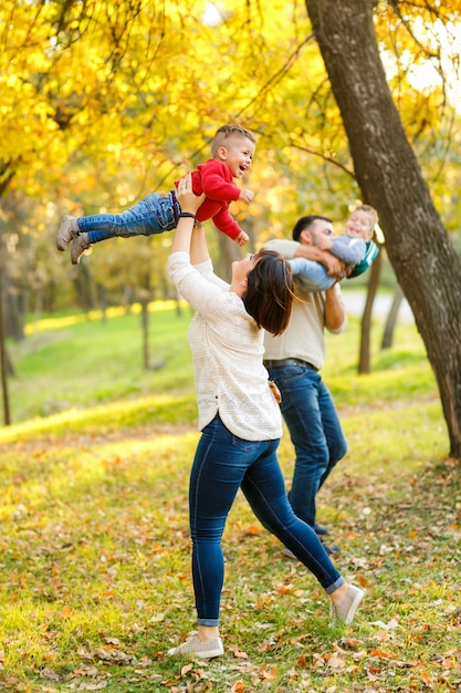 Familia feliz madre, padre y bebés gemelos están jugando y riendo en el parque