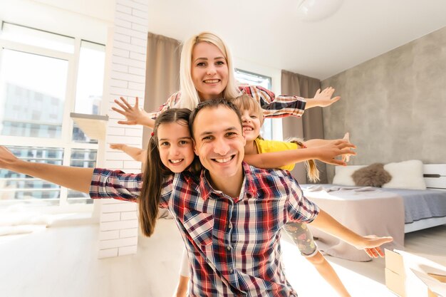 familia feliz madre, padre y dos niños jugando y abrazándose en casa