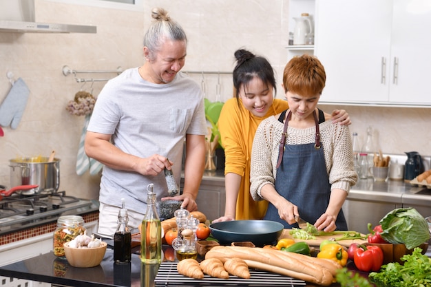 Familia feliz de madre padre e hija cocinando en la cocina haciendo comida sana juntos sintiéndose divertido