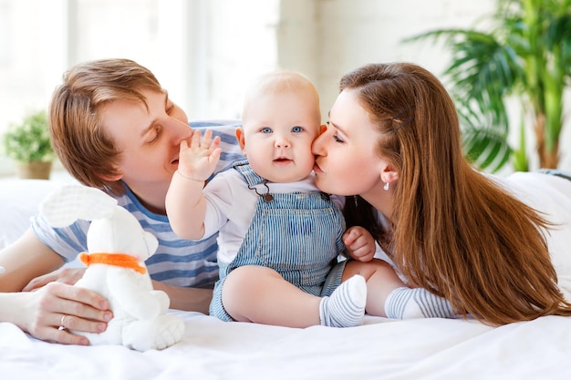 Familia feliz madre padre e hijo en la cama