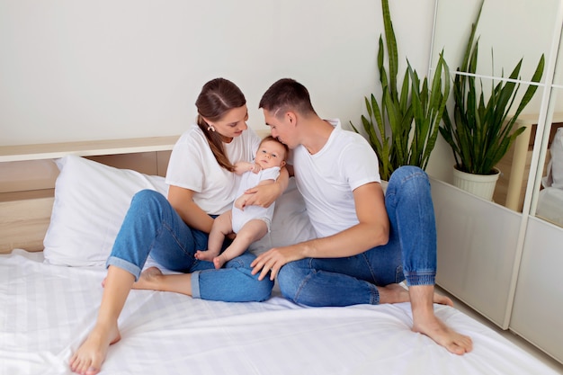 Familia feliz: madre, padre e hijo se encuentran en una cama blanca en el dormitorio.