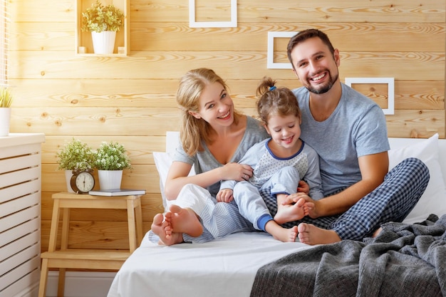 Familia feliz madre padre e hijo se ríe en la cama