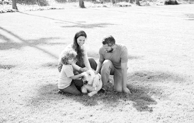 Familia feliz de madre papá e hijo jugando con perro mascota en el parque verde hierba verano