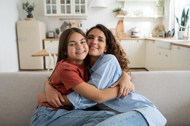 Foto familia feliz madre soltera e hija adolescente mejores amigas abrazándose mientras están sentadas en el sofá en casa