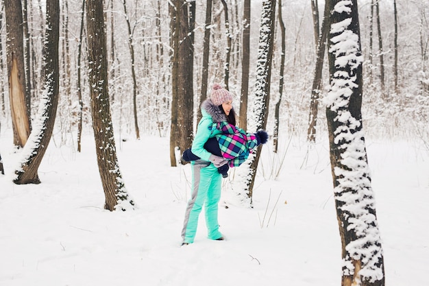 Família feliz mãe e filha bebê em uma caminhada de inverno na floresta.