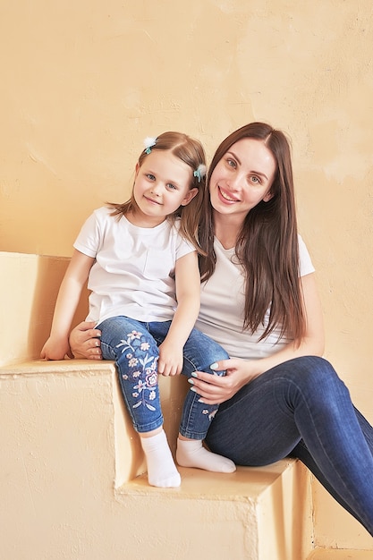 Família feliz. Mãe e filha em casa. Mulher jovem e menina. Dia das mães e das crianças. Bom dia e conceito de amor. Interior claro da casa.