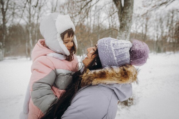 Família feliz mãe e filha se divertem jogando no inverno caminhar ao ar livre. retrato de inverno de mãe e filho.