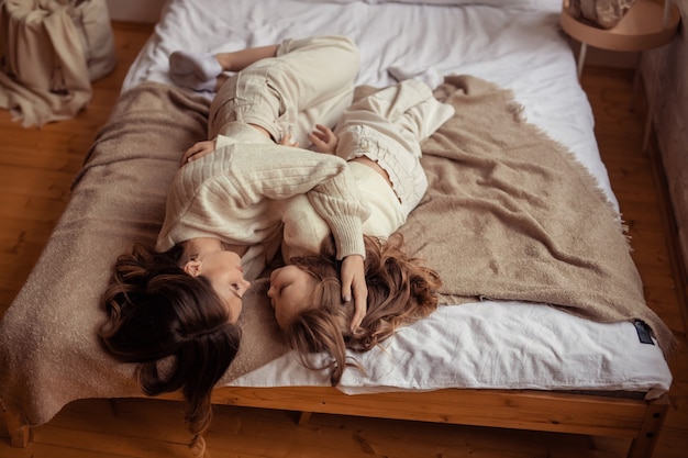 Família feliz mãe e filha se divertindo em casa na cama