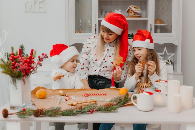 Família feliz, mãe e filhos, filho e filha fazem biscoitos de gengibre para o Natal na cozinha.