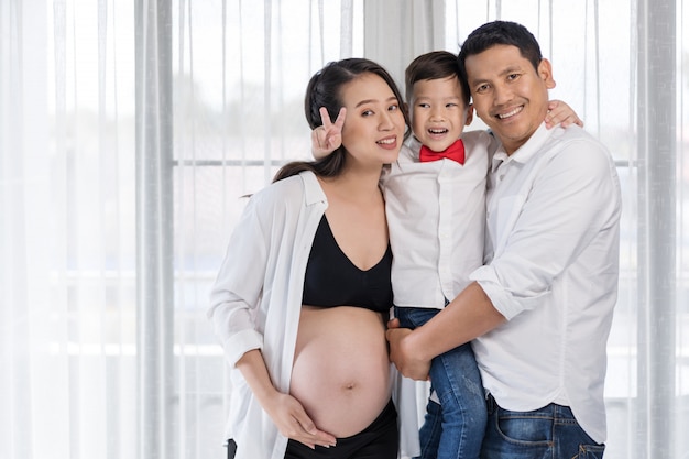 Família feliz, mãe grávida, pai e filho abraçando