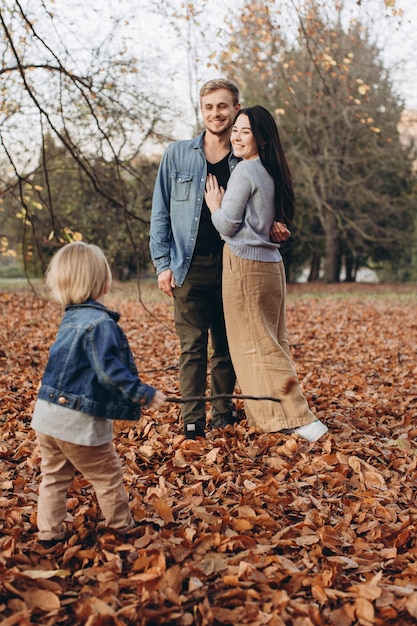 Família feliz, mãe, pai e bebê em passeio de outono no parque