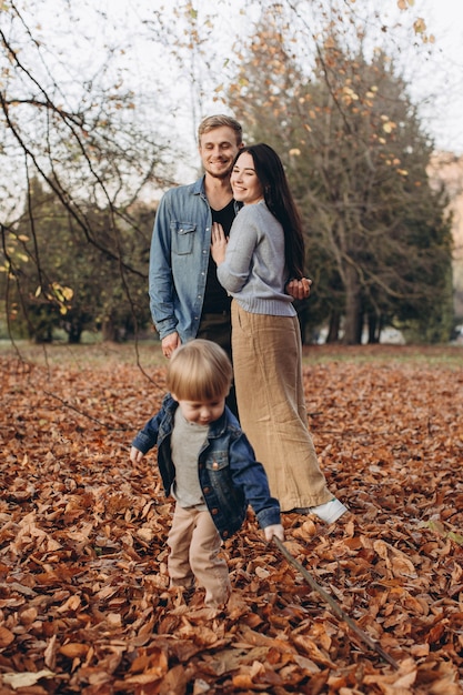 Família feliz, mãe, pai e bebê em passeio de outono no parque