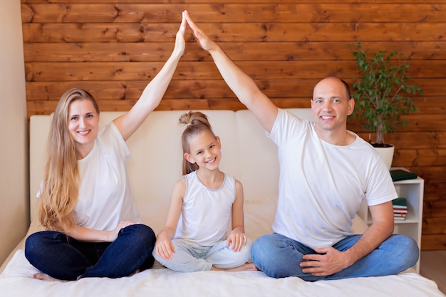 Família feliz, mãe, pai e filha na cama em casa no quarto