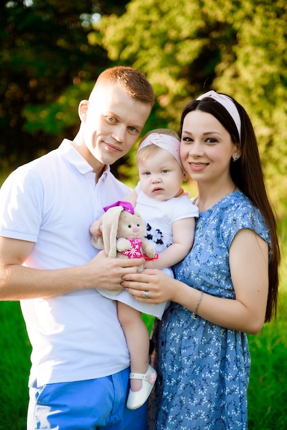 Família feliz: mãe pai e filha na natureza, no pôr do sol.