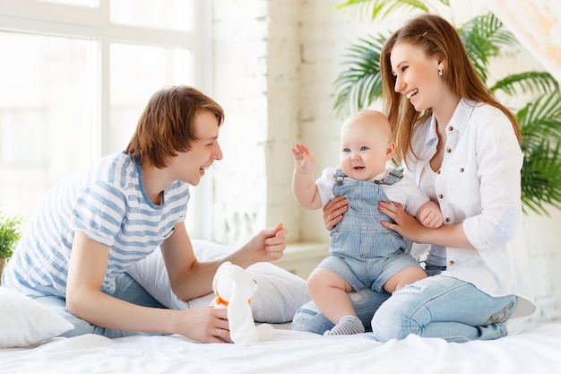 Família feliz mãe pai e filho bebê na cama