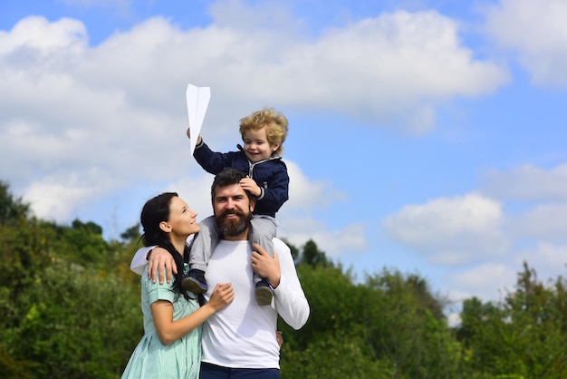 Família feliz mãe pai e filho filho rindo e se divertindo com avião de papel de brinquedo criança brincando com w