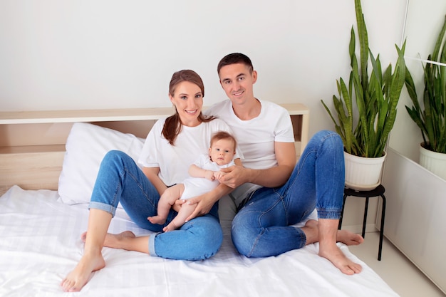 Família feliz: mãe, pai e filho menino deitar em uma cama branca no quarto.