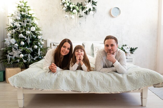 Família feliz, mãe, pai e filhos na manhã de Natal na cama