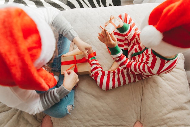 Familia feliz, mamá e hijo, abrazándose y dando regalos en la cama en la mañana de Navidad. Navidad.