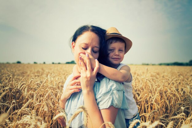 Familia feliz Mamá e hijo se ríen y hablan en el campo de trigo Vista frontal