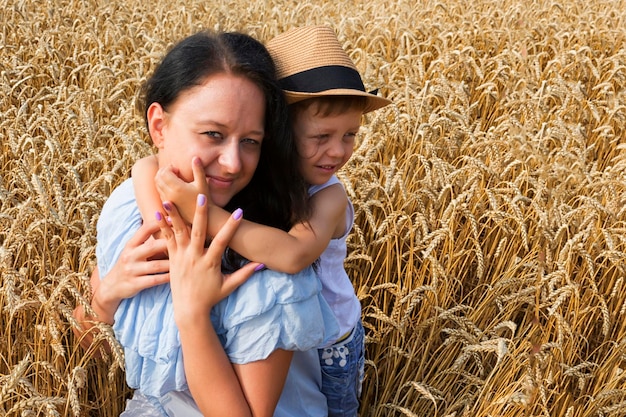 Familia feliz Mamá e hijo se ríen y hablan en el campo de trigo Vista frontal