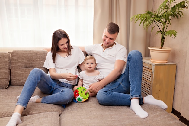 Familia feliz, mamá y papá juegan con su pequeña hija, pasan tiempo juntos