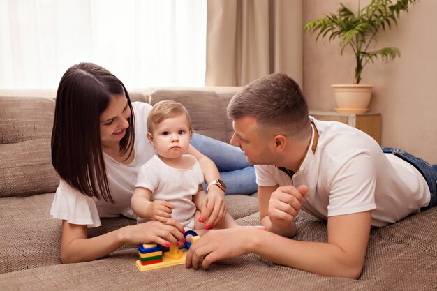 Familia feliz, mamá y papá juegan con su pequeña hija, pasan tiempo juntos