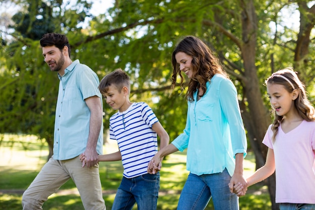 Familia feliz con la mano caminando en el parque