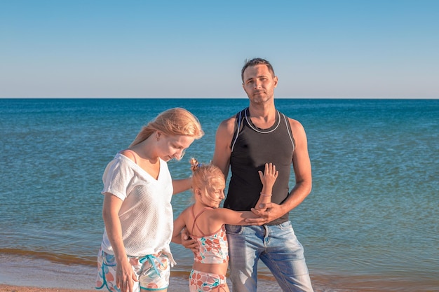 Familia feliz en el mar Un hombre, una mujer y un niño caminan por la orilla del mar Vacaciones de verano viajes y turismo