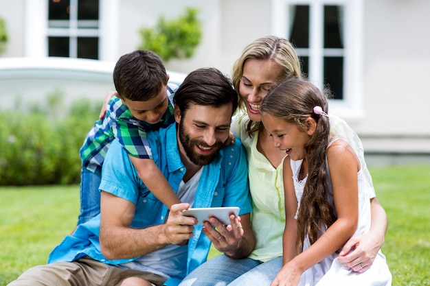 Familia feliz mirando el teléfono móvil en el patio