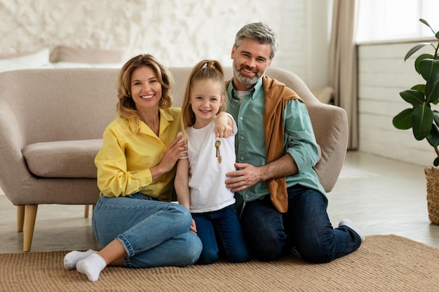 Família feliz mostrando a nova chave da casa sorrindo sentado em casa