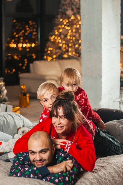 Família feliz na cama perto da árvore de Natal