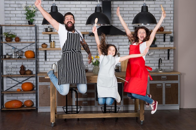 Família feliz na cozinha aproveitando a manhã Pai e filha Menina com pais de avental Mãe e pai com menina Pai mãe e filho chef cozinhando Mãe e filha na cozinha