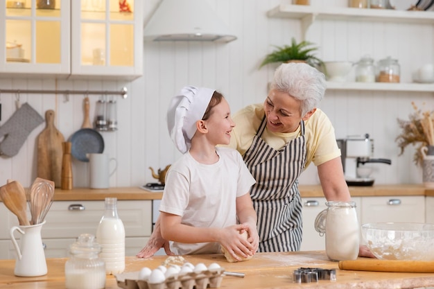 Família feliz na cozinha avó e neta cozinham juntos na cozinha avó ensinando