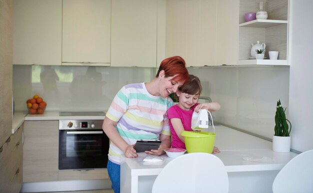 Família feliz na cozinha jogando e aprendendo a cozinhar enquanto fica em casa durante o isolamento pandêmico de coronavírus covid-19. Filha de mãe e filho preparando o bolo e biscoitos.