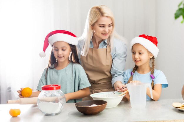 Família feliz na cozinha. Mãe e duas filhas preparando a massa para biscoitos de Natal.