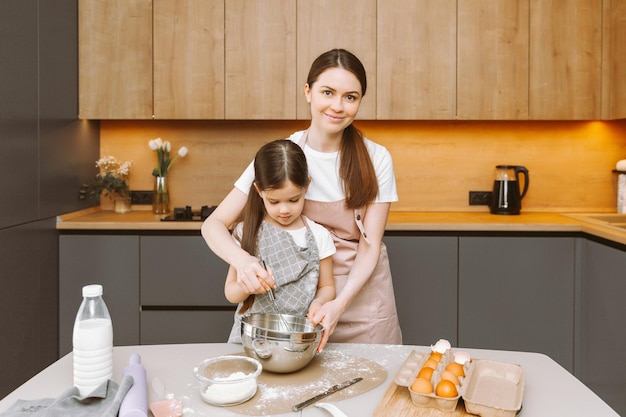 Família feliz na cozinha mãe e filha preparam massa assar biscoitos bolo de Páscoa