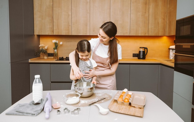 Família feliz na cozinha mãe e filha preparam massa assar biscoitos bolo de Páscoa