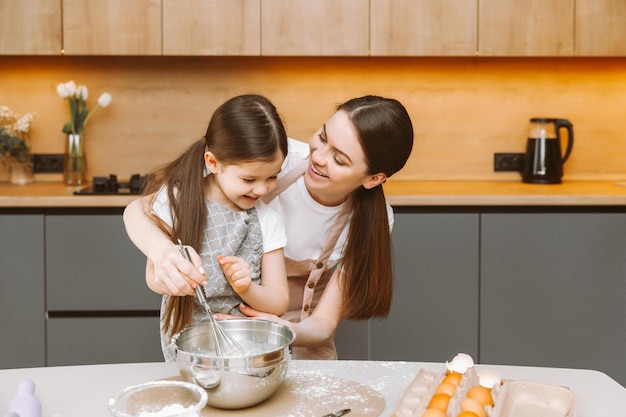 Família feliz na cozinha mãe e filha preparam massa assar biscoitos bolo de Páscoa