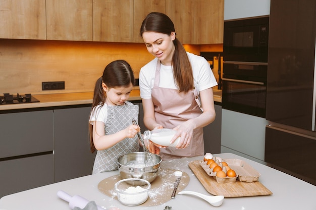 Família feliz na cozinha mãe e filha preparam massa assar biscoitos bolo de Páscoa